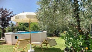 Un bain à remous doté d’un auvent, deux chaises longues et une petite piscine, le tout situé dans un jardin.