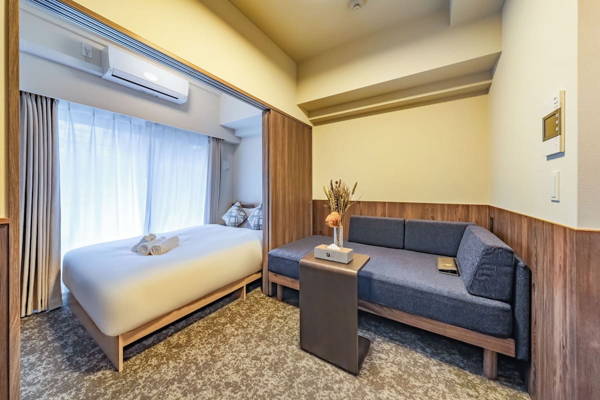 Een hotelkamer met een bed, een bank, een klein tafeltje en een airconditioner.
