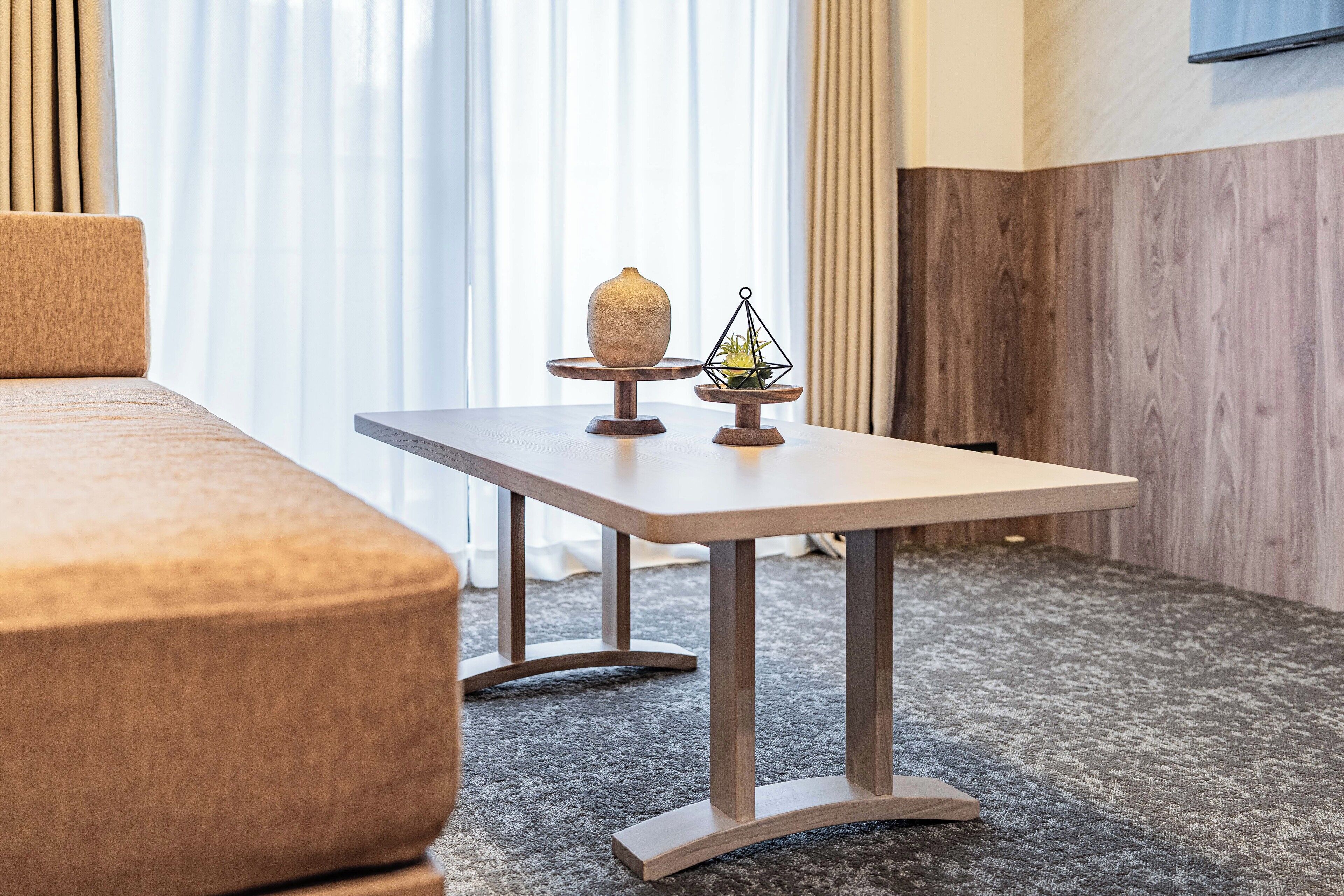 A modern hotel room with a wooden table, a vase, and a geometric decoration.