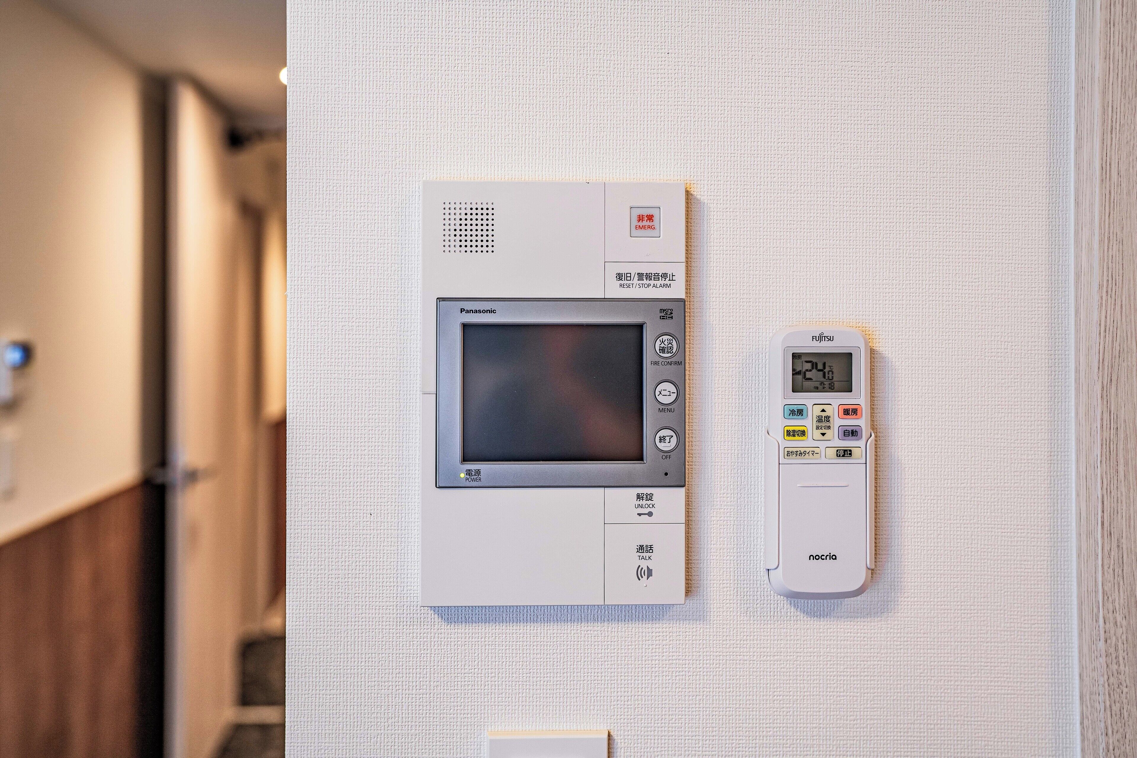 A wall-mounted control panel with a digital display and buttons, likely for room amenities.