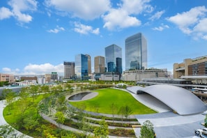 Un paysage urbain moderne caractérisé par des immeubles de grande hauteur, un grand parc central et un élément architectural distinctif en forme de courbe.
