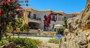 A hotel with a pool, outdoor seating, and a rocky landscape.
