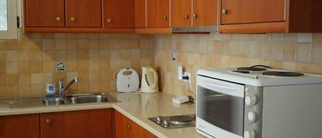 A kitchen with wooden cabinets, a white microwave, a kettle, and a toaster.