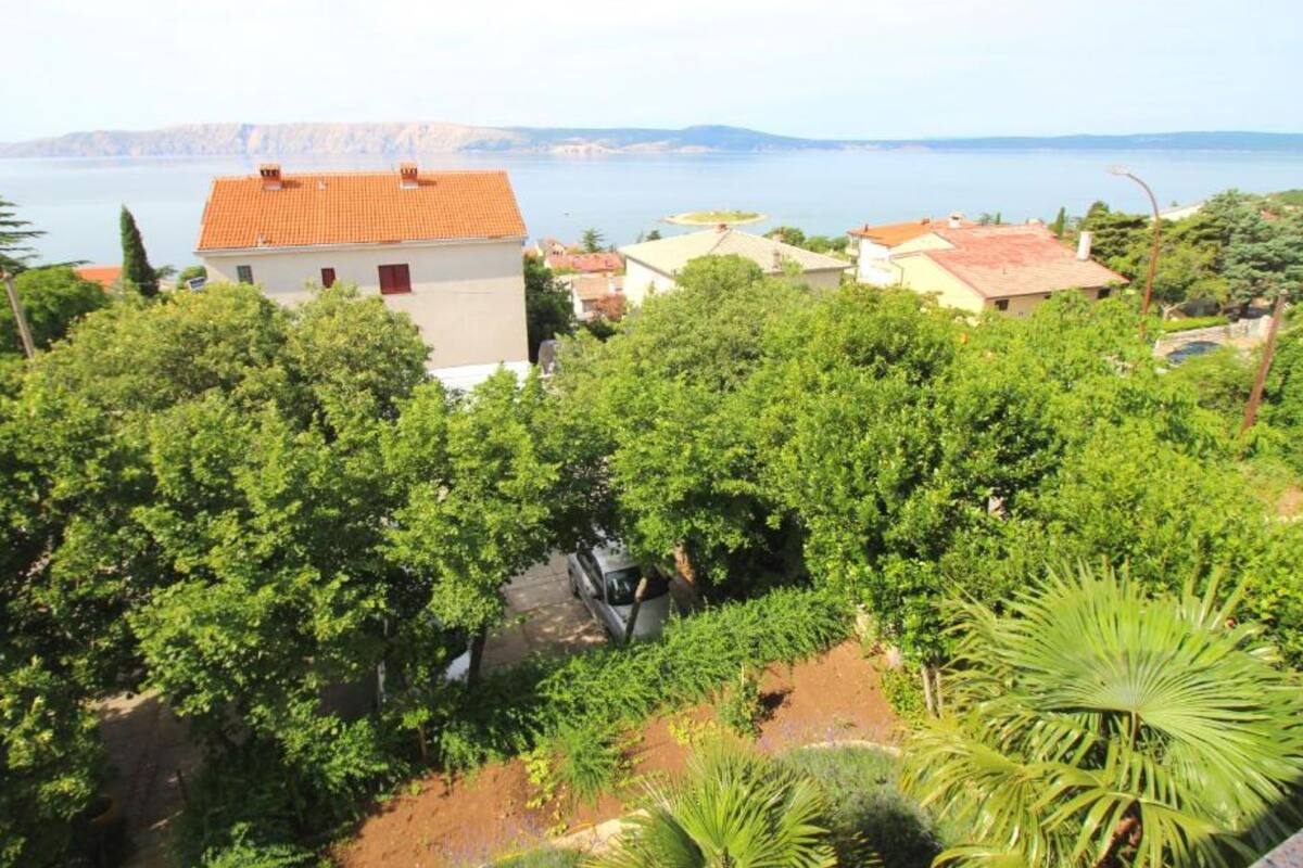 A coastal residential area with houses, lush greenery, and a view of the sea.