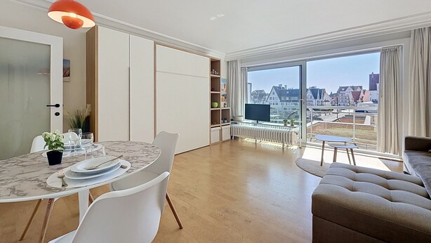 Una sala de estar moderna con comedor, ventanas amplias y vistas a la ciudad.