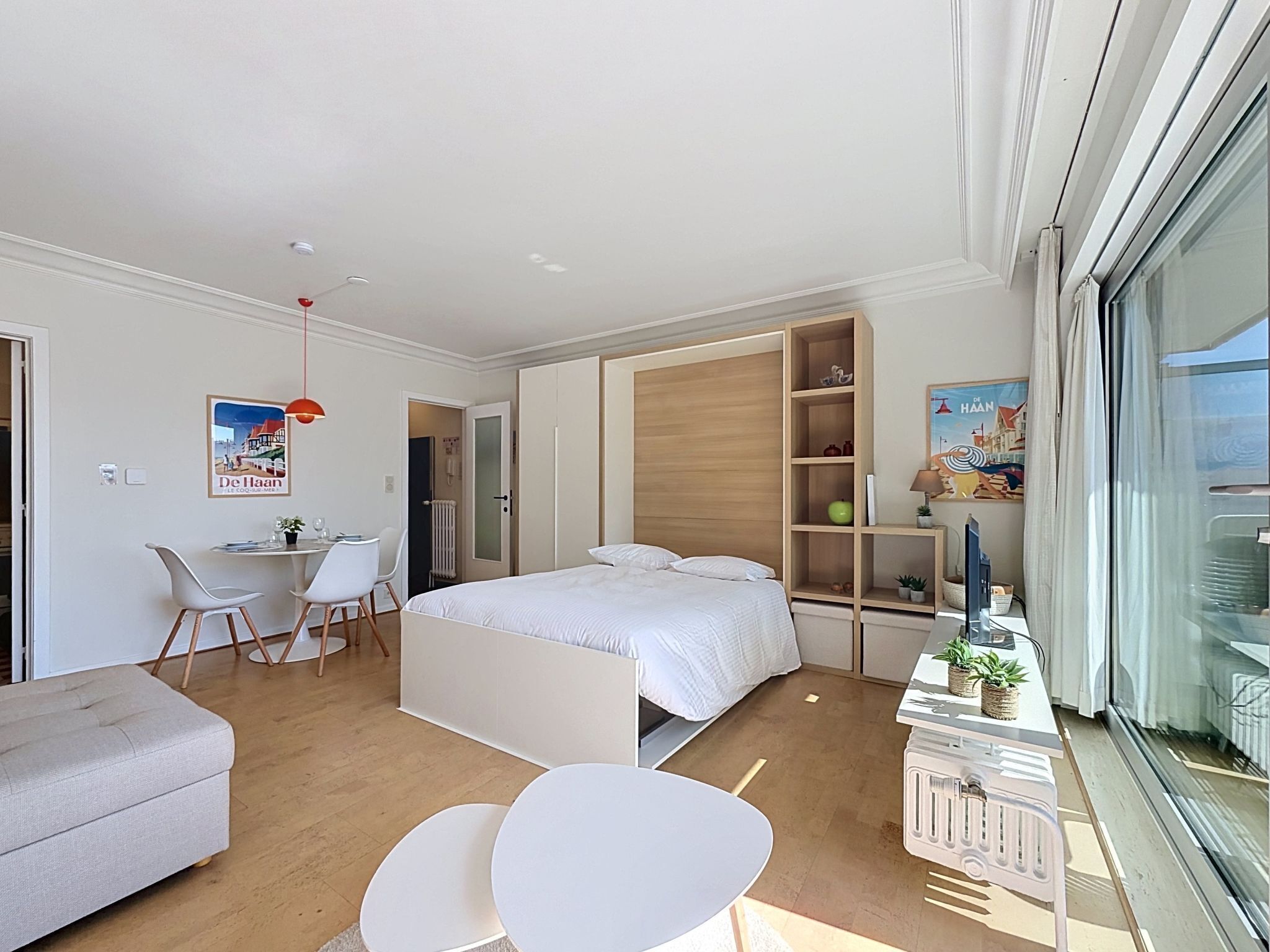 Een moderne slaapkamer met een bed, een bureau, een stoel, een bank en een raam.
