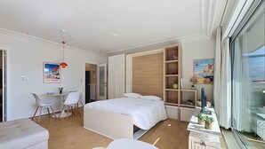 Un dormitorio moderno con cama, escritorio, silla, sofá y ventana.