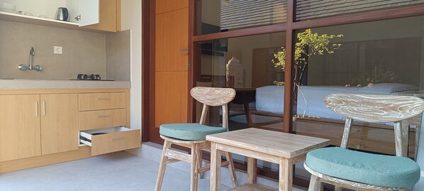 Una cocina moderna con armarios de madera, horno empotrado y pileta. Hay un comedor con mesa y sillas de madera, y un ventanal con vistas al exterior.