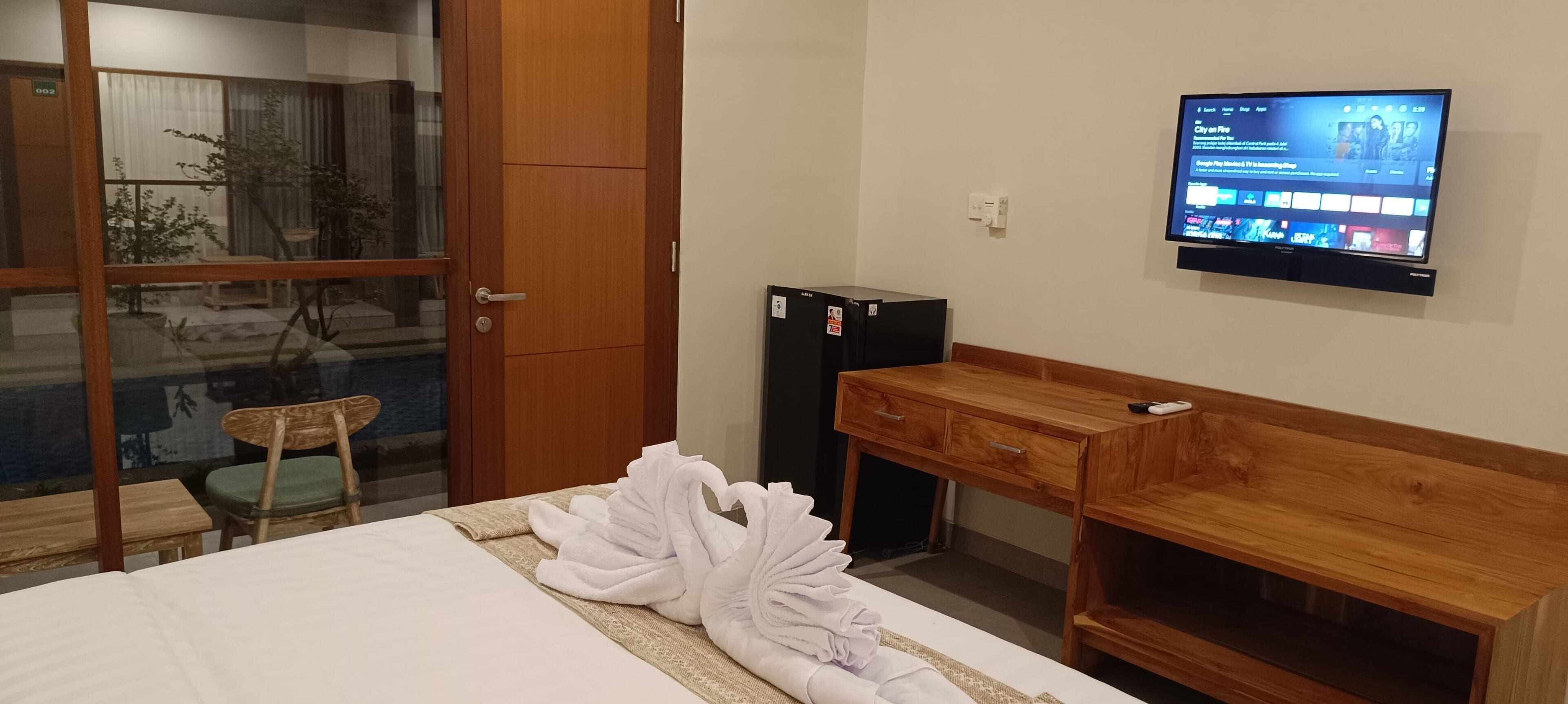 Ein Hotelzimmer mit Bett, einem Holztisch, einem Fernseher und einer Schiebetür zu einem Balkon.