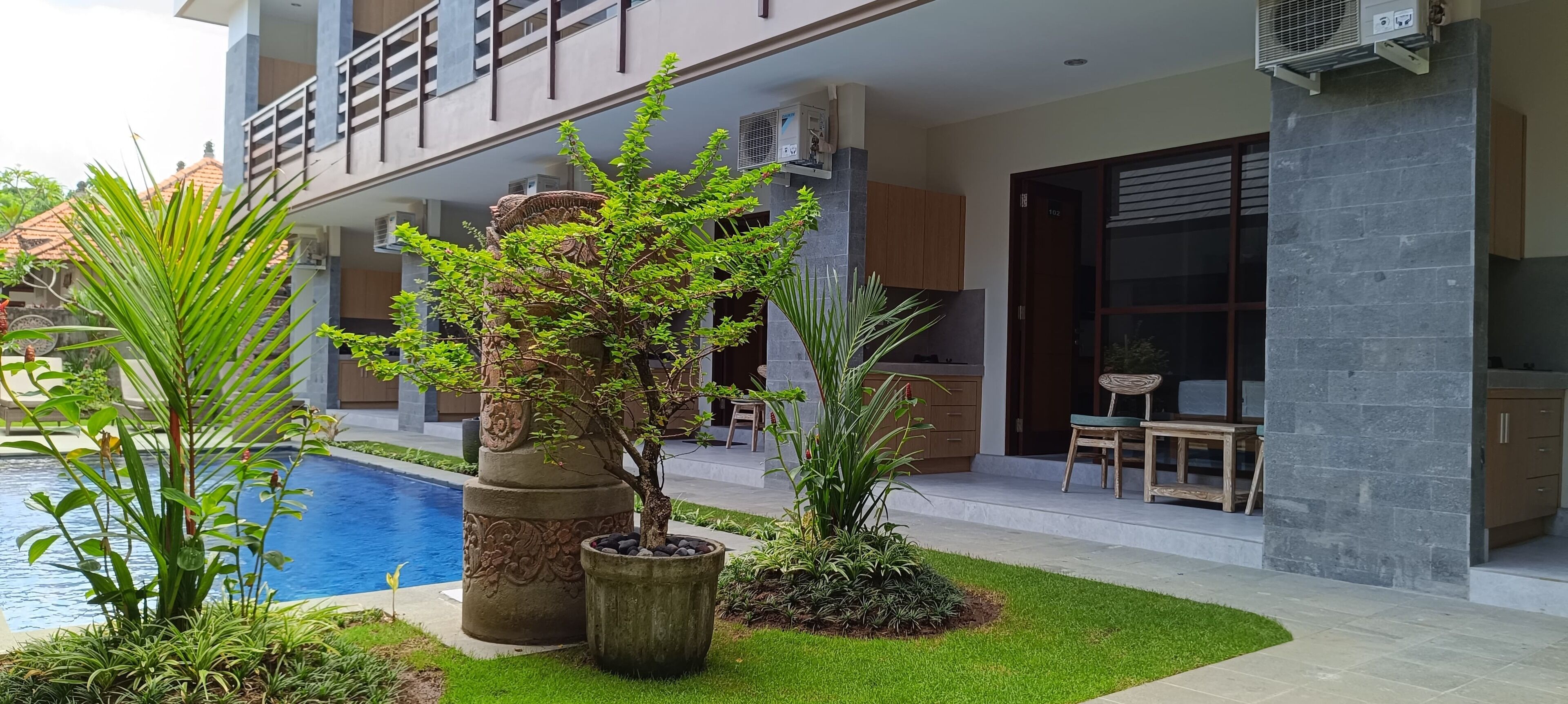 Un bâtiment moderne doté d’une piscine, d’un espace extérieur aménagé et de plantes décoratives.