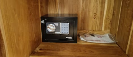A black safe with a keypad and a lock, placed on a wooden shelf.