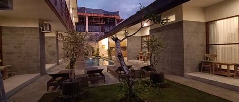 A courtyard with a swimming pool, seating areas, and potted plants.