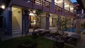 Une maison moderne dotée d’un vaste espace extérieur comprenant une piscine, un coin salon extérieur et un escalier menant à un niveau supérieur.