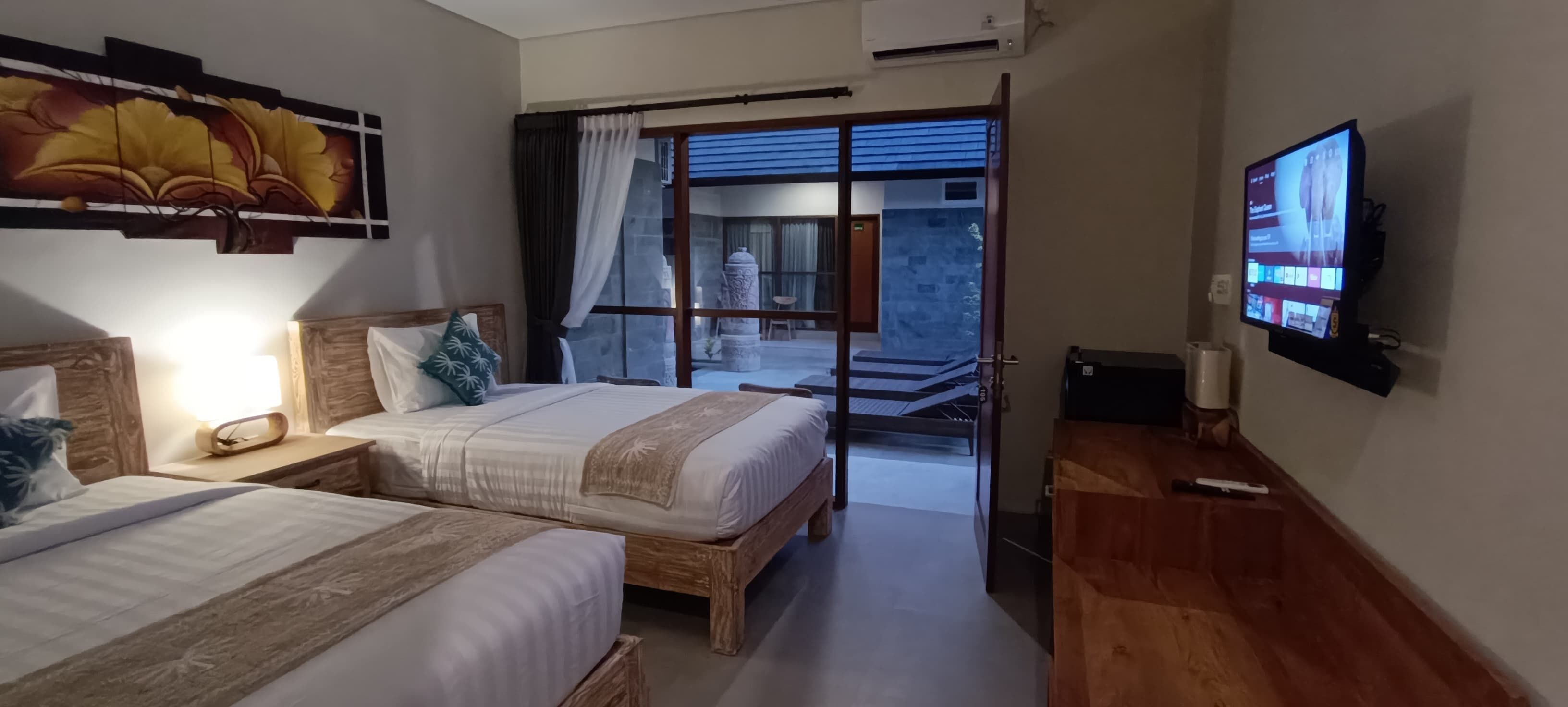 A hotel room with two beds, a TV, and a view of the outside.