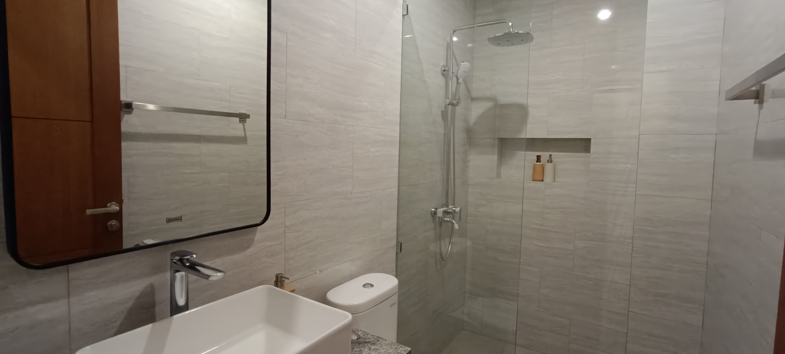 A modern bathroom with a glass-enclosed shower, a white sink, and a toilet.