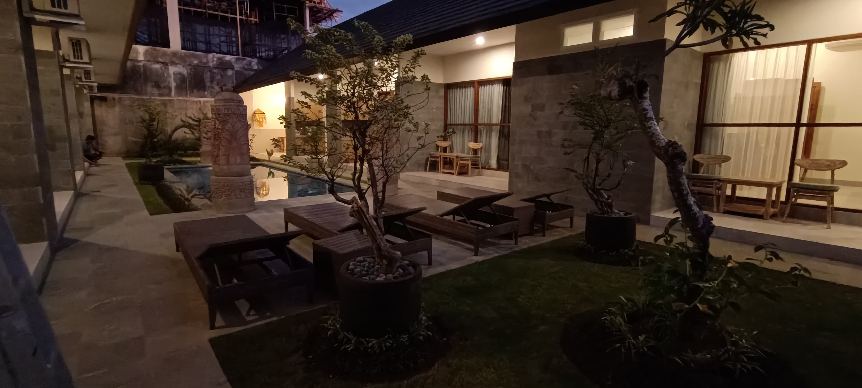 A courtyard with outdoor seating, a pool, and a building with large windows.