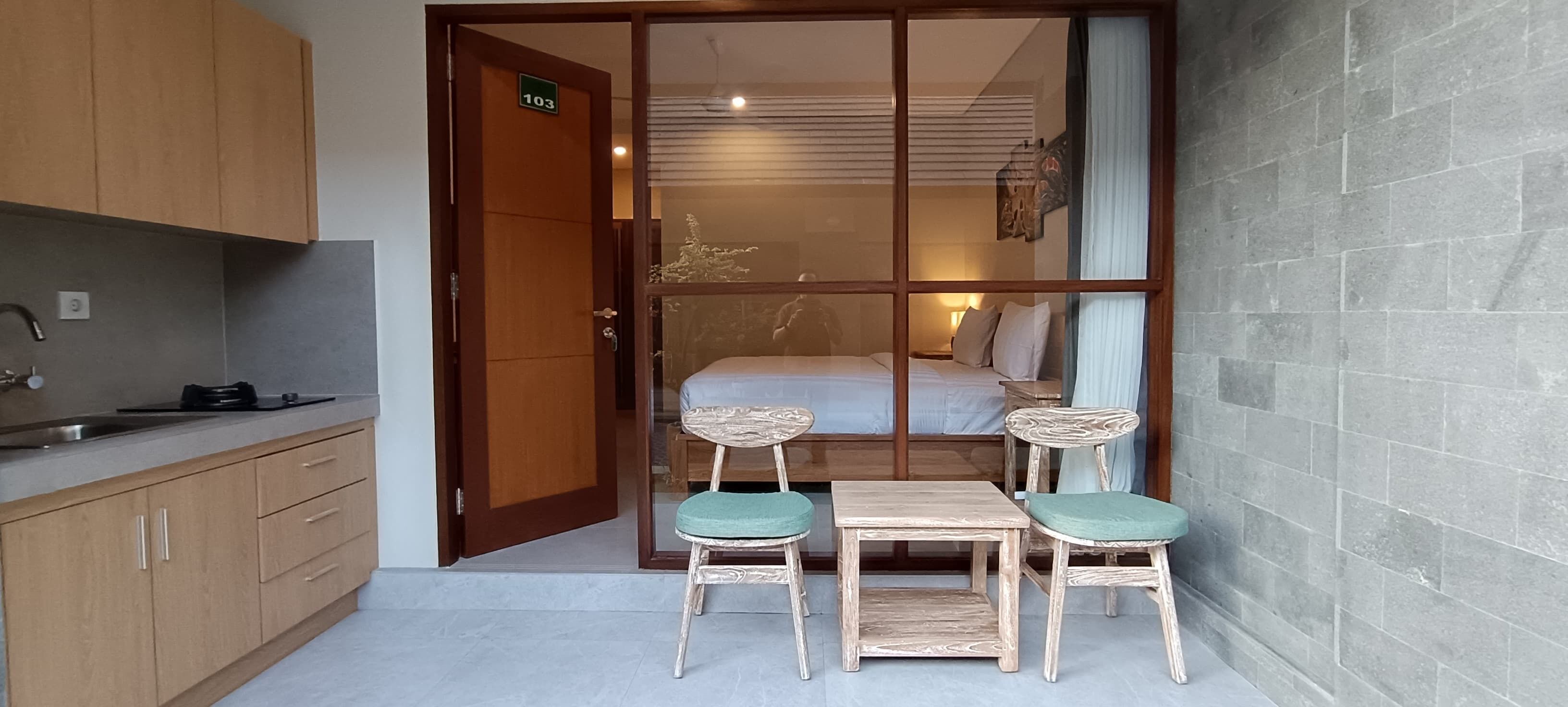 Habitación compacta con kitchenette, una cama y comedor con dos sillas y una mesa.