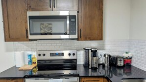 A kitchen with wooden cabinets, a stainless steel microwave, an oven, a coffee maker, a toaster, and a sink. - 2-bedroom Guest Suite in SW Calgary with WiFi (Calgary)
