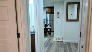 A hallway with wooden flooring leading to a kitchen area with a dining table and chairs. - 2-bedroom Guest Suite in SW Calgary with WiFi (Calgary)