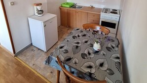 A compact kitchen with a refrigerator, stove, and wooden cabinets.