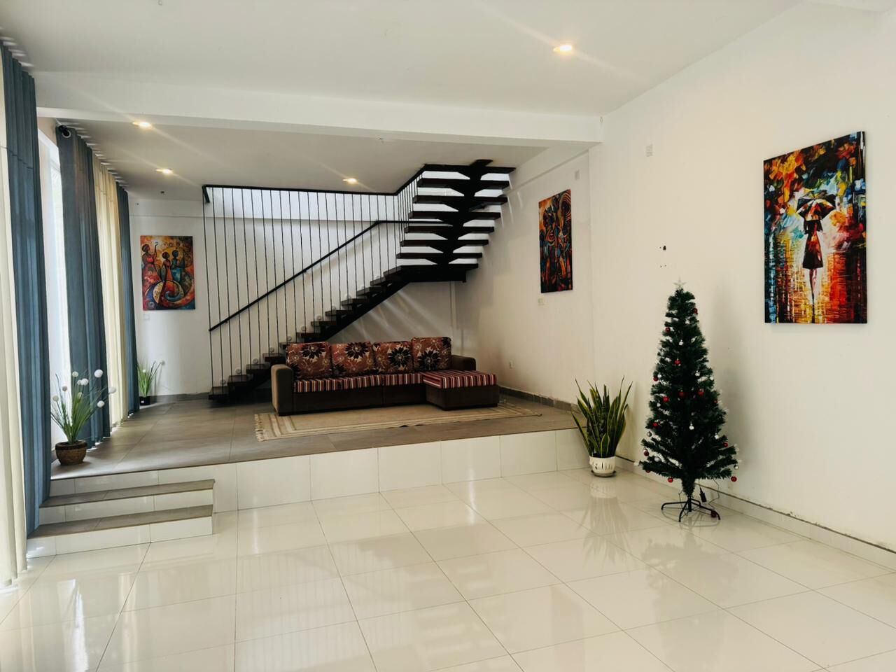 Un vestíbulo amplio con una escalera moderna, una zona de estar y decoración navideña.