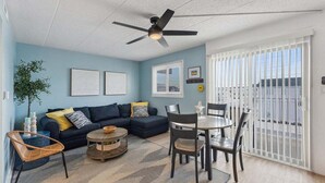 Ein Wohnzimmer mit Sofa, Couchtisch, Sesseln und Deckenventilator.