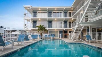 A hotel with a pool, multiple balconies, and a staircase.