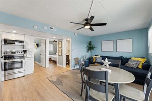 Une cuisine moderne avec des armoires blanches, un four encastré et un ventilateur de plafond.