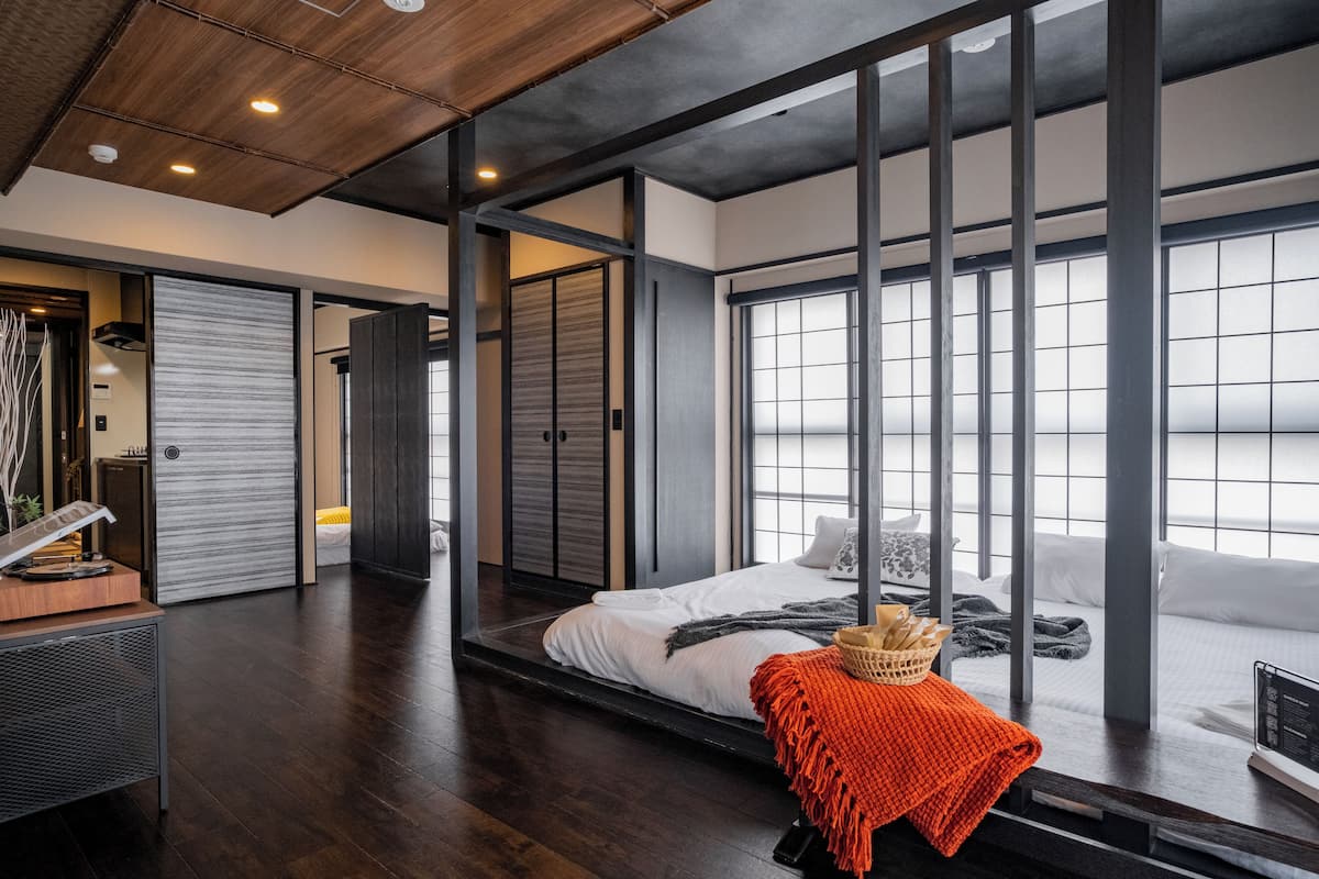 Ein modernes Hotelzimmer mit einem großen Bett, Schiebetüren und Blick auf die Stadt.
