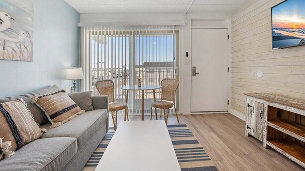 Un salon comprenant un canapé, des fauteuils, une table basse, un téléviseur et un balcon avec vue.