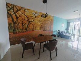 A modern living room with a dining area, a large mural of a tree-lined path, a sofa, and a balcony with a view.