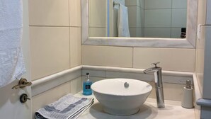 Ein Badezimmer mit einem weißen Waschbecken, einem Spiegel und einem Handtuchhalter.