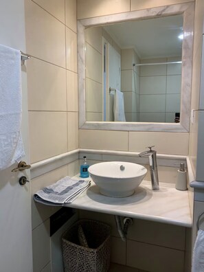 Une salle de bain avec un lavabo blanc, un miroir et un porte-serviettes.