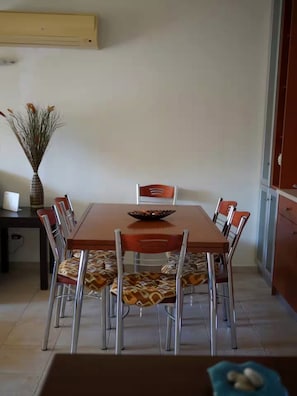 A dining area with a wooden table, six chairs, and a vase of dried flowers. - Cassiopeia 1BR Apt on Beach with Pool (Pyrgos Psilonerou)