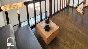 A spacious room with a wooden floor, a balcony with a wooden railing, and a view of the outdoors through a window. - Designer Island Villa with Stunning Panoramic Sea Views (Bizen)