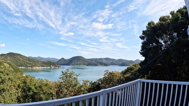 A deck with a view of a lake and mountains. - Designer Island Villa with Stunning Panoramic Sea Views (Bizen)