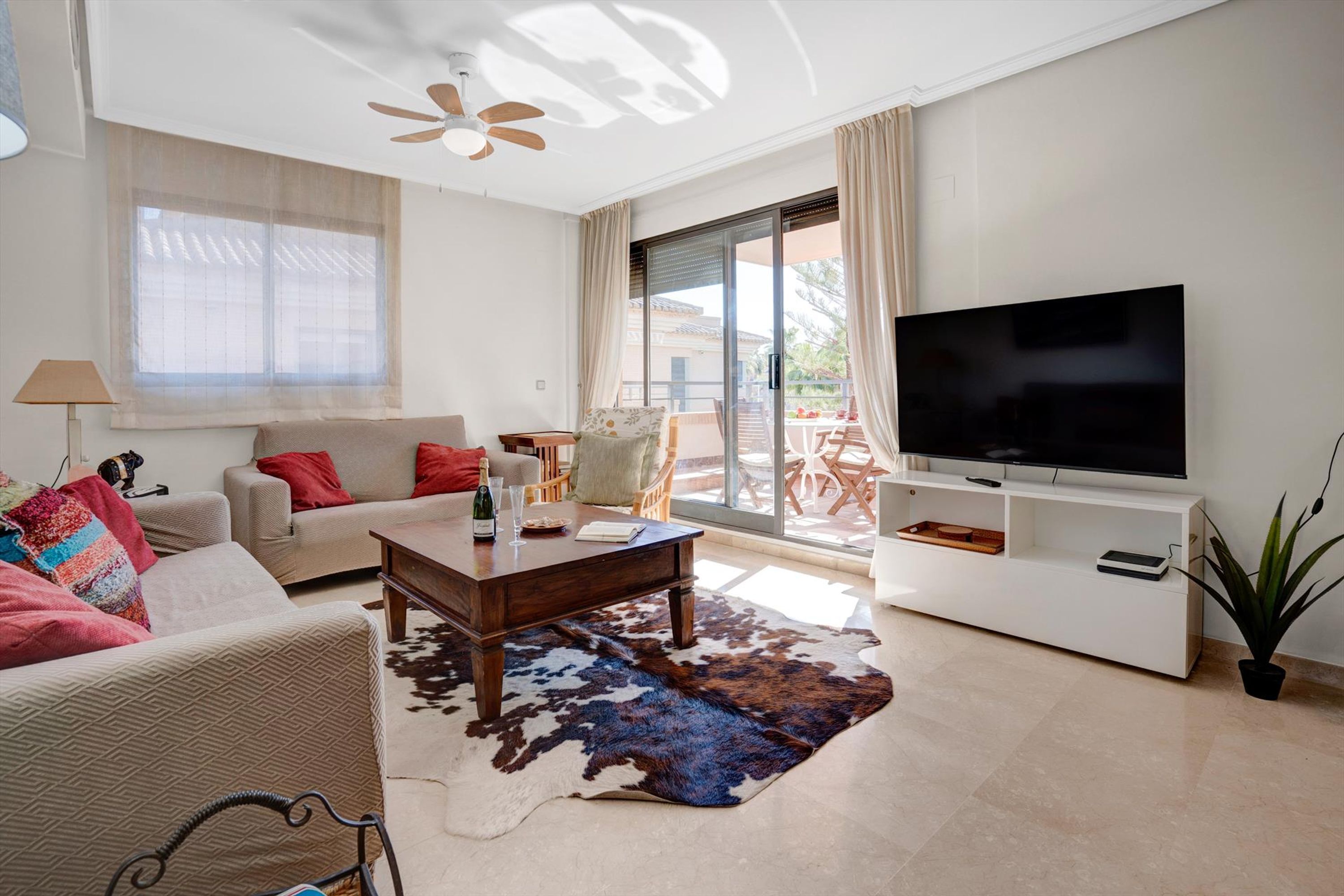 Una sala de estar moderna con un sofá, una mesa de centro y un televisor de pantalla plana sobre un mueble blanco.