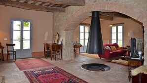 A rustic interior with stone walls, a fireplace, wooden furniture, and a red sofa. - Casale Rigo in San Casciano dei Bagni (San Casciano dei Bagni)