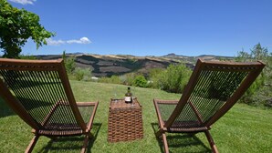 Two wicker chairs facing a scenic view of hills and a bottle of wine on a woven table. - Casale Rigo in San Casciano dei Bagni (San Casciano dei Bagni)