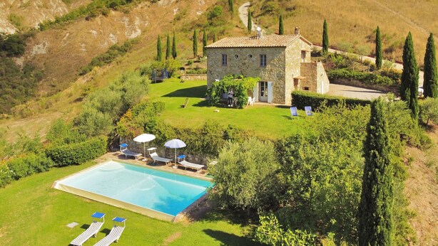 A stone house with a swimming pool, surrounded by lush greenery and hills. - Casale Rigo in San Casciano dei Bagni (San Casciano dei Bagni)