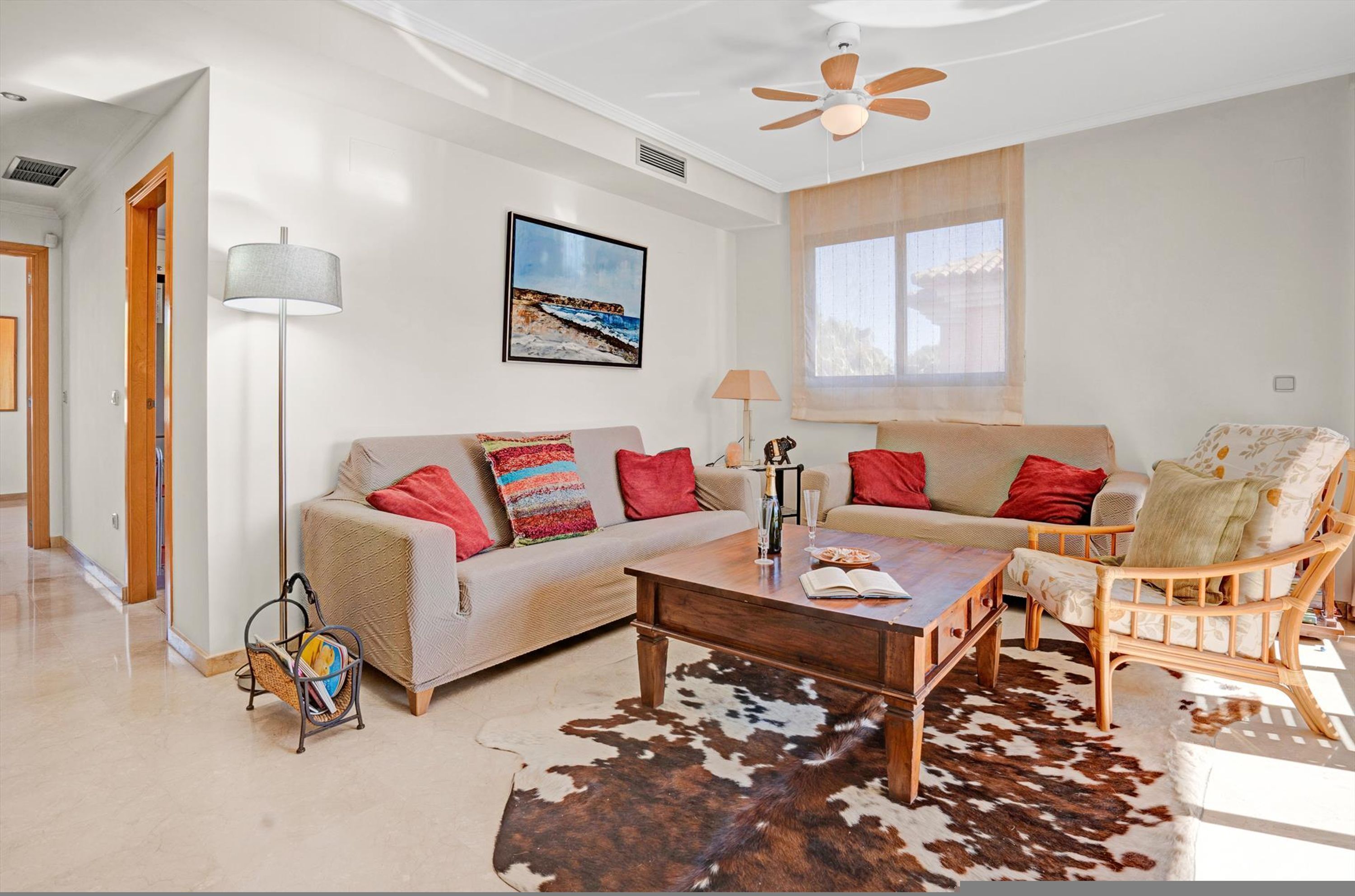 A living room with a sofa, armchair, coffee table, and a cowhide rug.