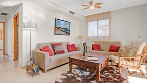 Una sala de estar con sofá, sillón, mesa de centro y alfombra de cuero de vaca.