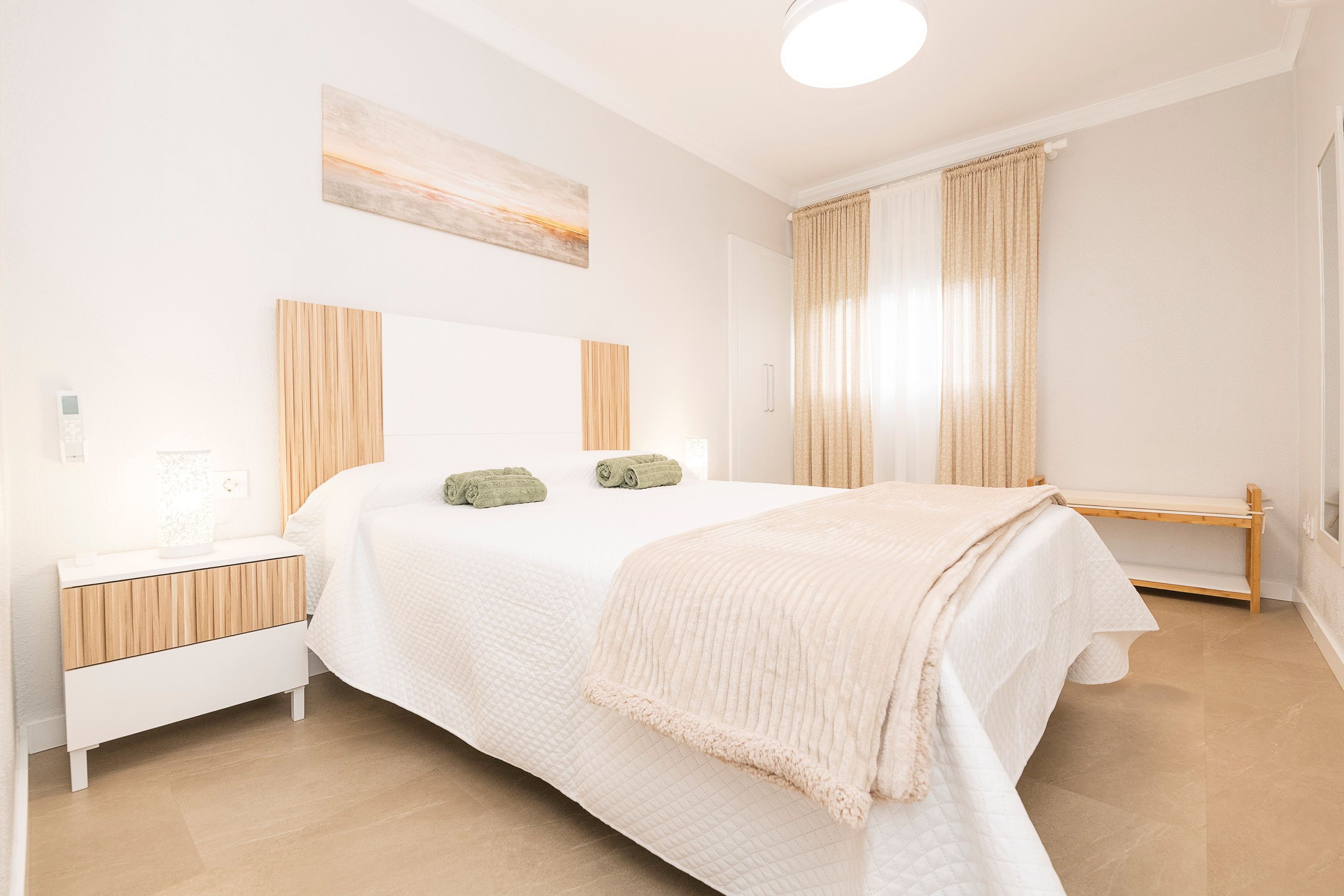 A bedroom with a bed, bedside table, and a window with curtains.