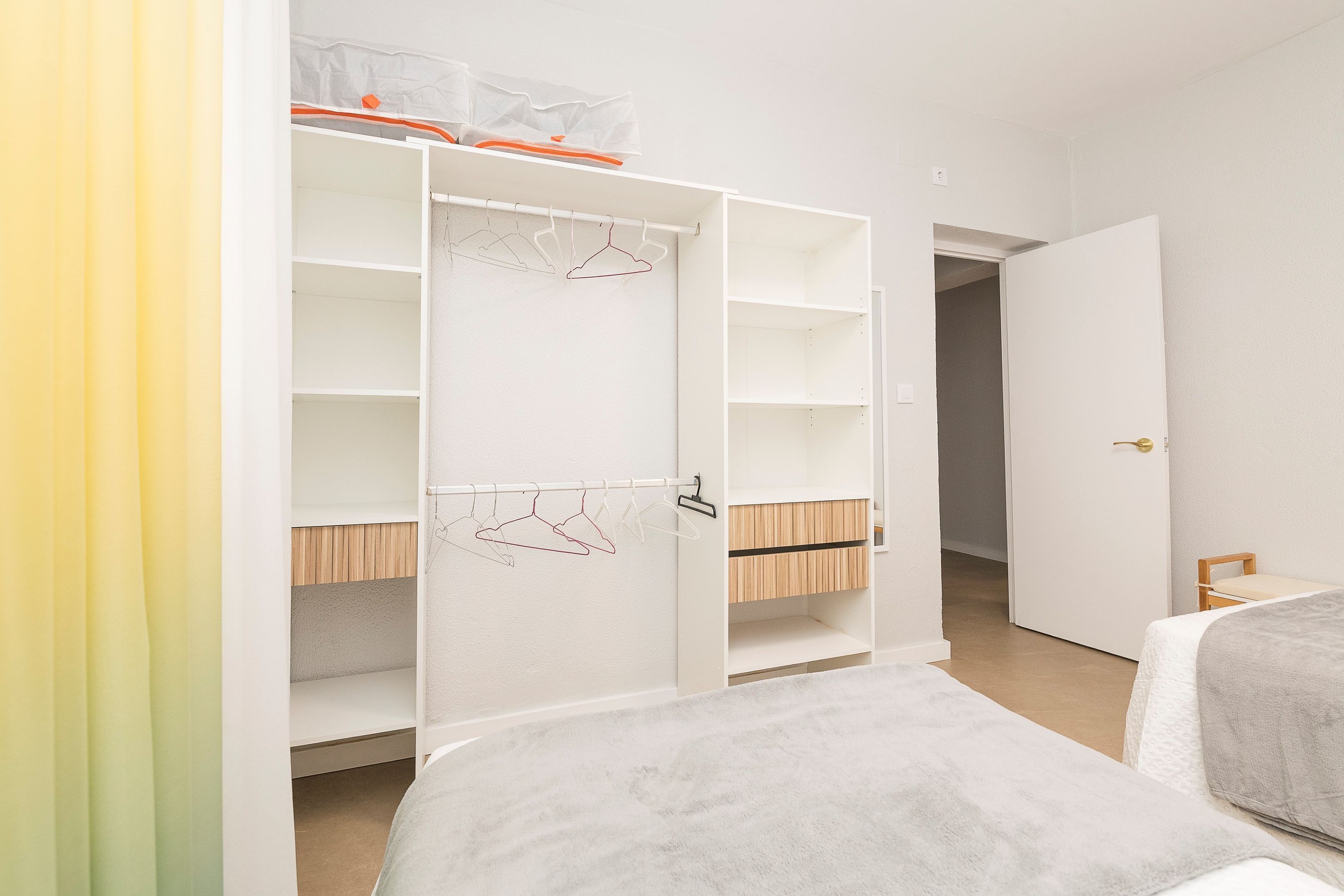 Une chambre à coucher comprenant un lit, une armoire et une porte donnant sur une autre pièce.