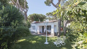 A white house with a tiled roof, surrounded by lush greenery and two white lounge chairs. - Las Camelias in Chiclana de la Frontera (Chiclana de la Frontera)