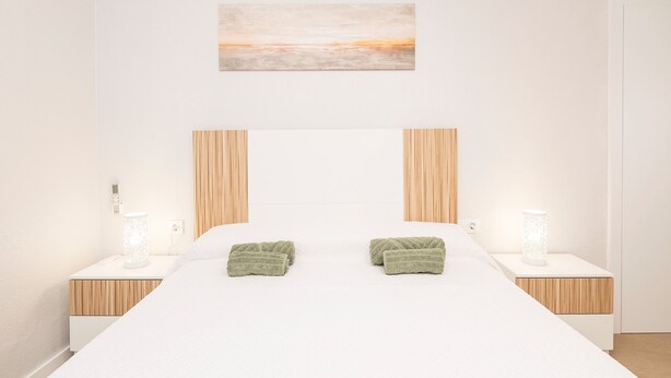 A modern bedroom with a large bed, two bedside tables with lamps, and a painting on the wall. - Las Camelias in Chiclana de la Frontera (Chiclana de la Frontera)
