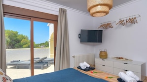 Ein Hotelzimmer mit Bett, Fernseher, Blick ins Freie, einem Holzschrank und einem Vorhangfenster.