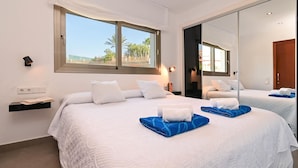 A hotel room with a large bed, a bedside table, a nightstand, a window with a view, and a mirror. - Casa Javi 8 pax in Platja de l Arenal (Javea)