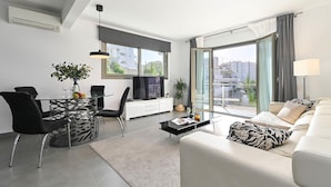 A modern living room with a glass dining table, black chairs, a sofa, and a TV. - Casa Javi 8 pax in Platja de l Arenal (Javea)