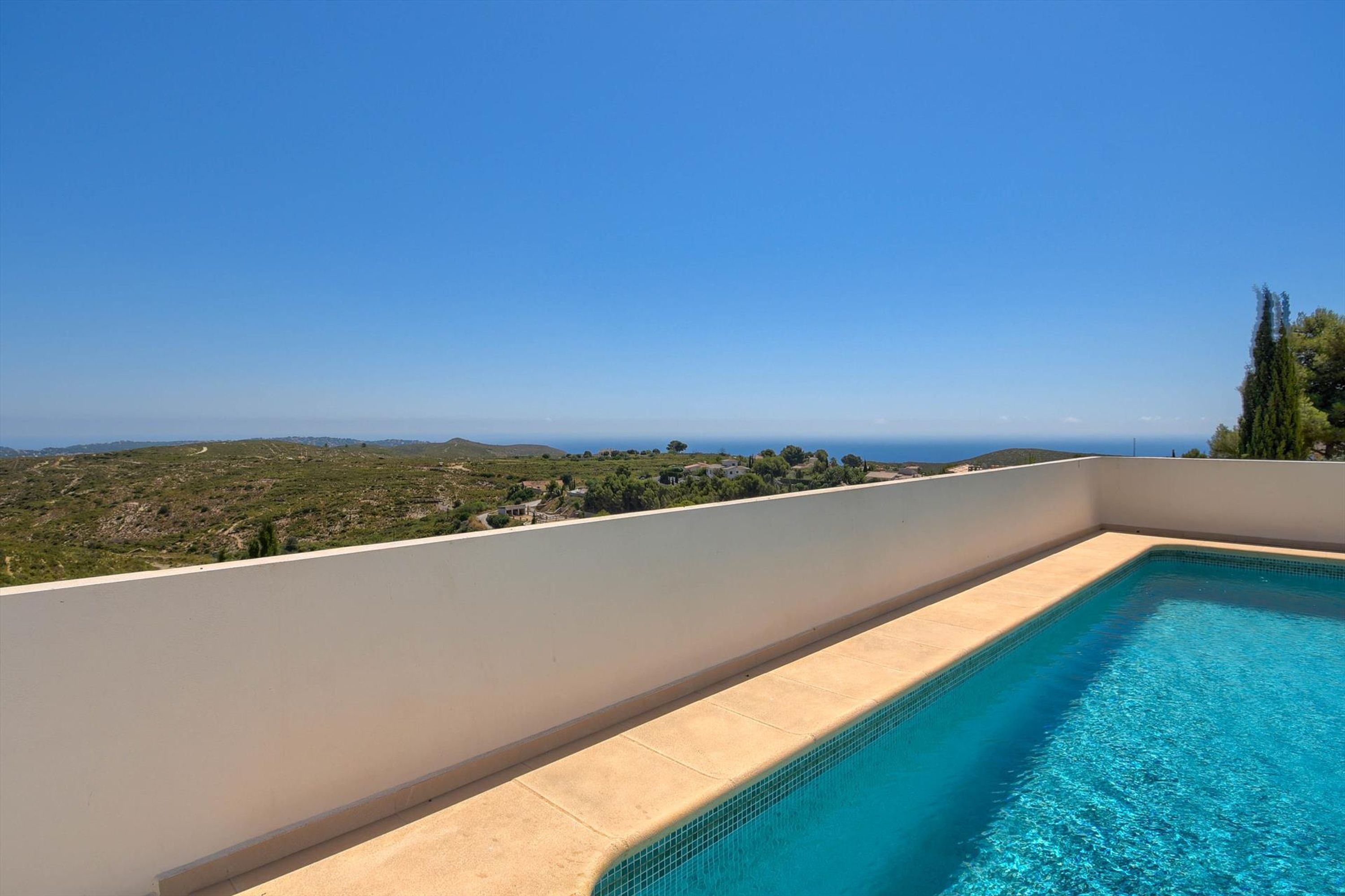 A rooftop swimming pool with a clear view of the landscape and the sea.